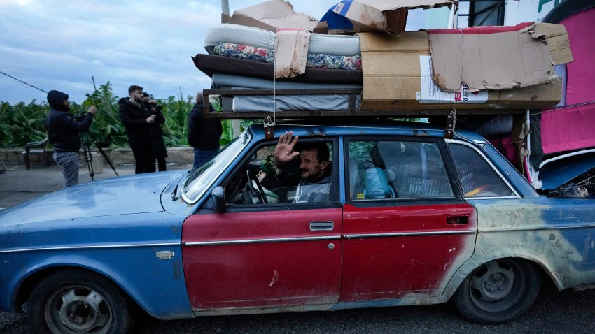 A man who is returning to his village waves as he carries his belongings on his car after the ceasefire between Hezbollah and Israel began early morning, in Tyre, south Lebanon, Wednesday, Nov. 27, 2024.