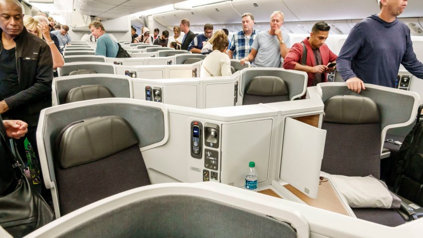 Passengers deplane through the business class seating area on an American Airlines flight, London Heathrow Airport, Aug. 14, 2018.