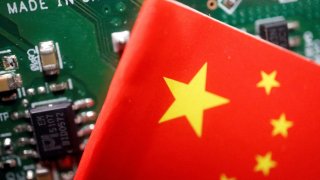 A Chinese flag is displayed next to a “Made in China” sign seen on a printed circuit board with semiconductor chips, in this illustration picture taken February 17, 2023.