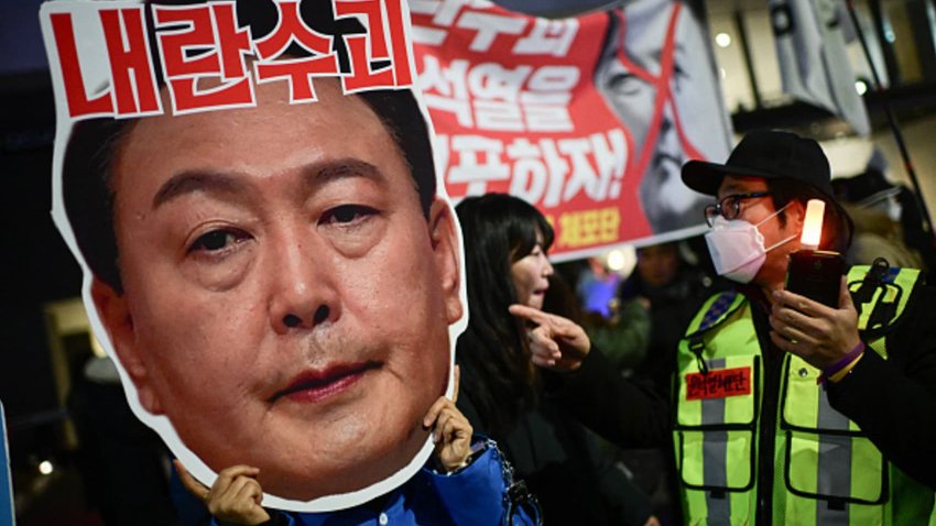 A protester holding a cardboard reading “Leader of insurgents” on an image depicting the face of South Korea’s President Yoon Suk Yeol takes part in a protest calling for his ouster outside the National Assembly in Seoul on December 8, 2024. 