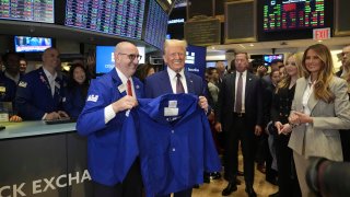 President-elect Donald Trump is handed a coat by trader Peter Giacchi, as he walks the floor of the New York Stock Exchange, Thursday, Dec. 12, 2024, in New York.