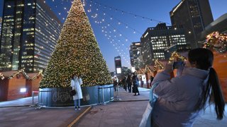 People posing for photos in front of a Christmas light installation in central Seoul on December 22, 2023.