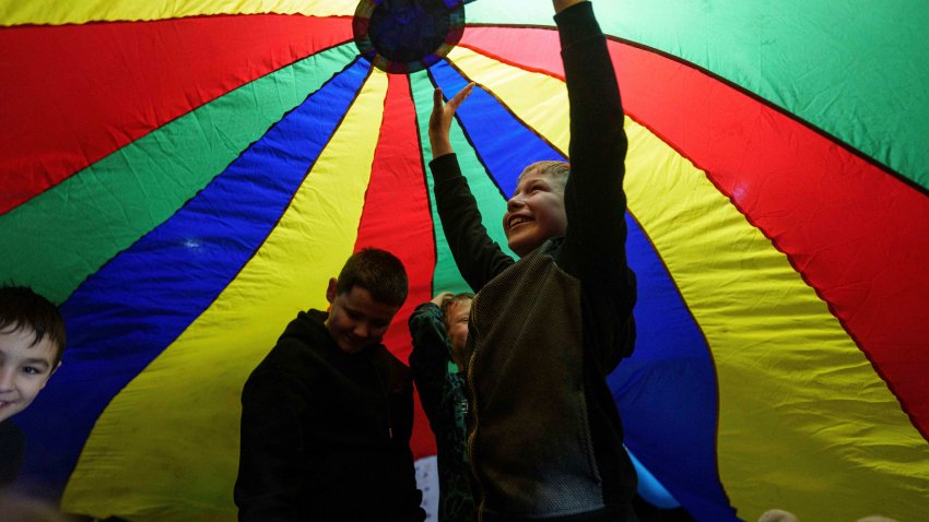 Children stand under a play parachute during an event organized by the local NGO Ukrainian Frontiers during celebration St. Nicholas Day in Izium, Ukraine, Dec. 6, 2024.