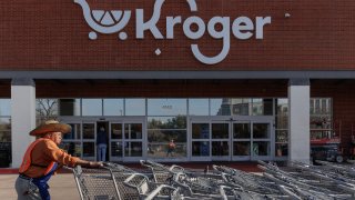 A worker pushes shopping carts outside a Kroger grocery store