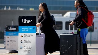 Travelers wait for an Uber ride-share vehicle at Los Angeles International Airport in Los Angeles on Feb. 8, 2023.