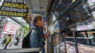 A man looks in the window of a money changer showing the rate of various currencies against the Japanese yen, along a street in central Tokyo on April 29, 2024. 