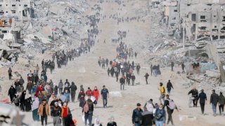 People walk towards their homes through the destroyed streets of Gaza City on January 19, 2025. T