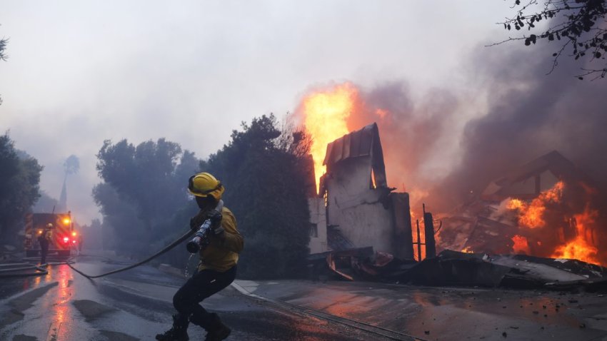 A firefighter battles the advancing Palisades Fire as it burns a structure in the Pacific Palisades neighborhood of Los Angeles, Tuesday, Jan. 7, 2025.