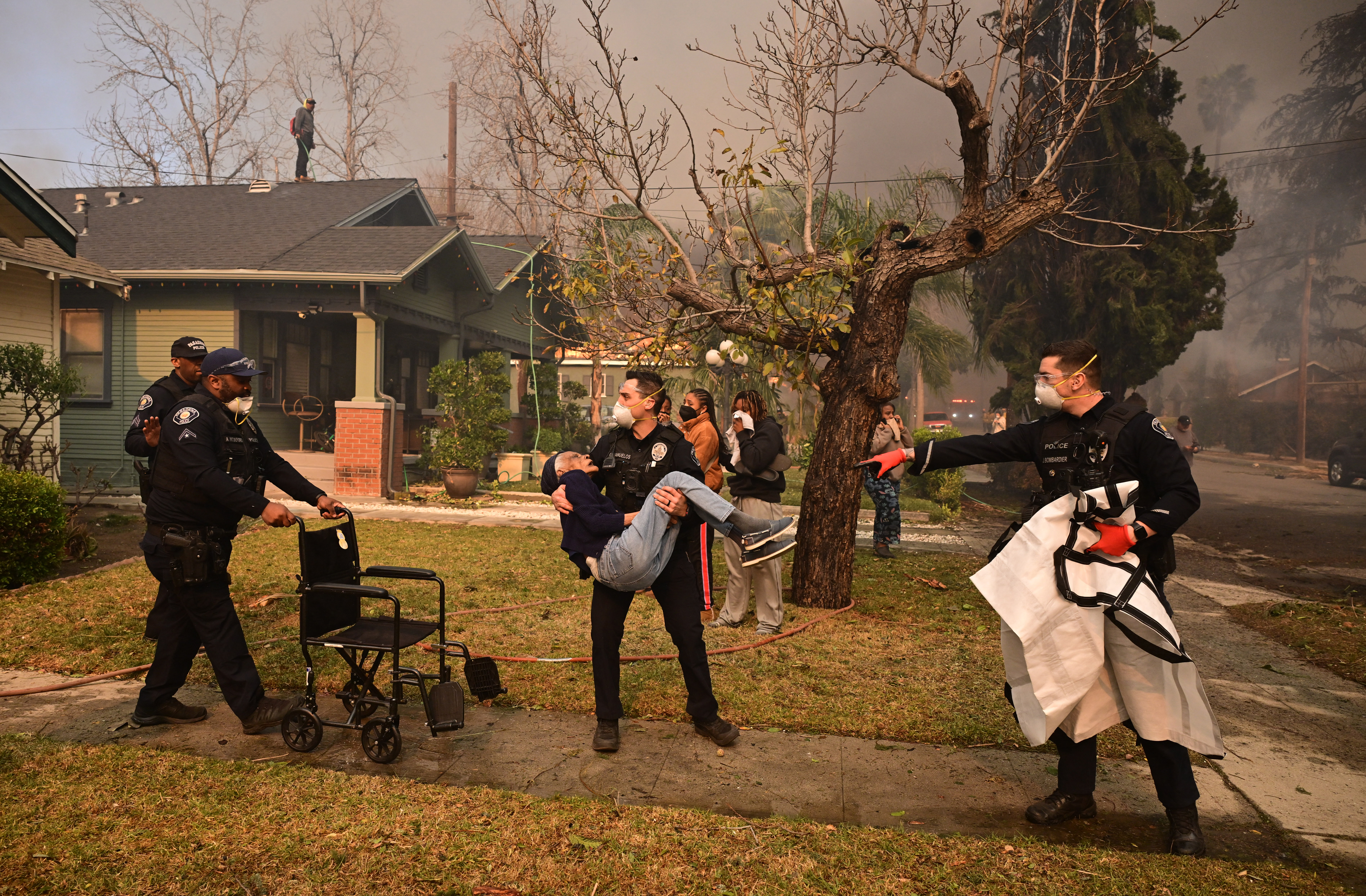 Police officers remove an elderly resident from her home during the Eaton Fire on January 8, 2025.