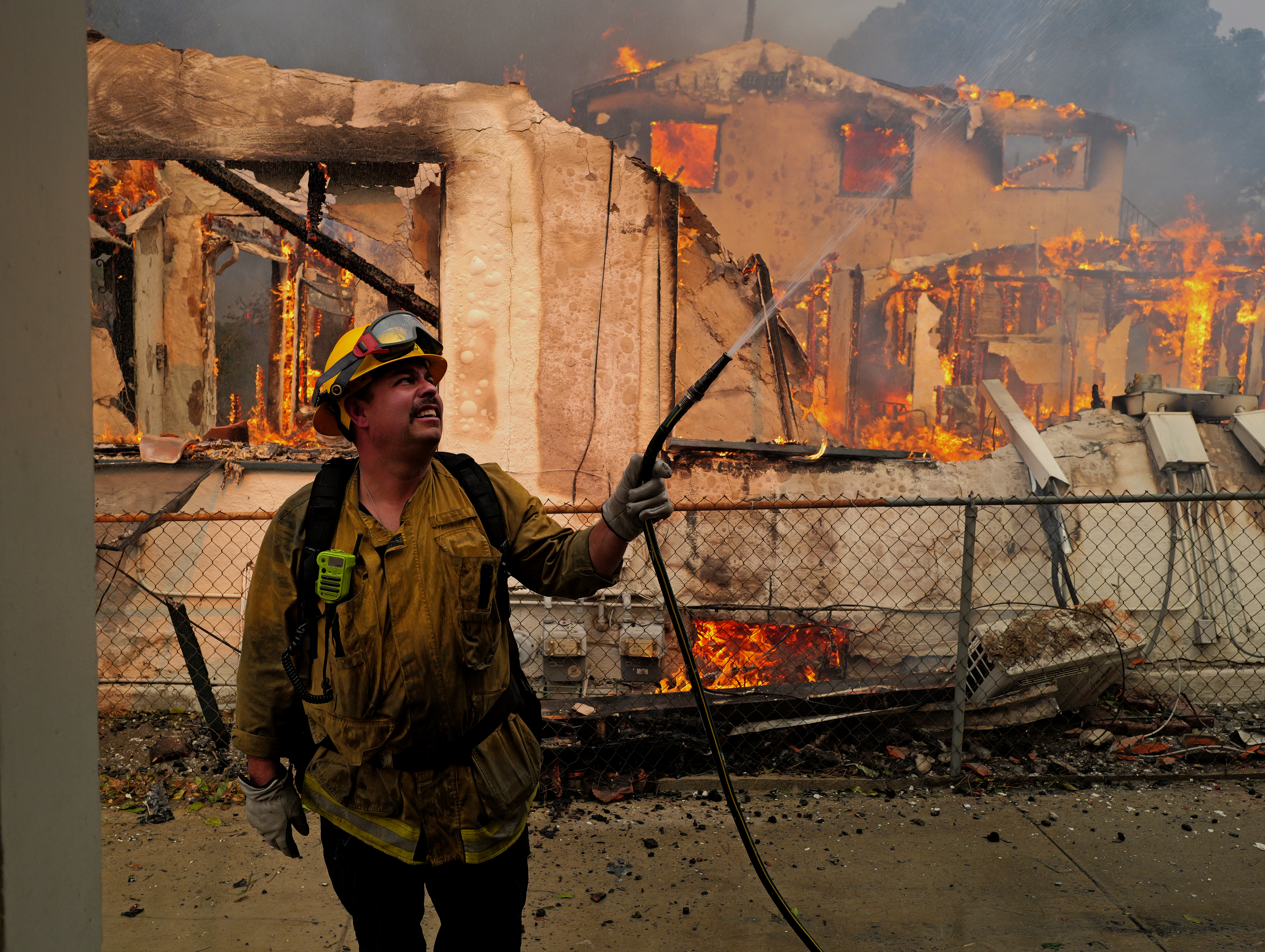 A firefighter sprays water on a house to protect it from the Eaton Fire in the Altadena neighborhood on January 08, 2025 in PASADENA, CALIFORNIA. A spokesperson for the Los Angeles County Sheriff’s Department said the death toll has risen, confirming three more people have died. Additionally, an undetermined amount of homes and businesses have been destroyed. (Photo by Nick Ut/Getty Images)