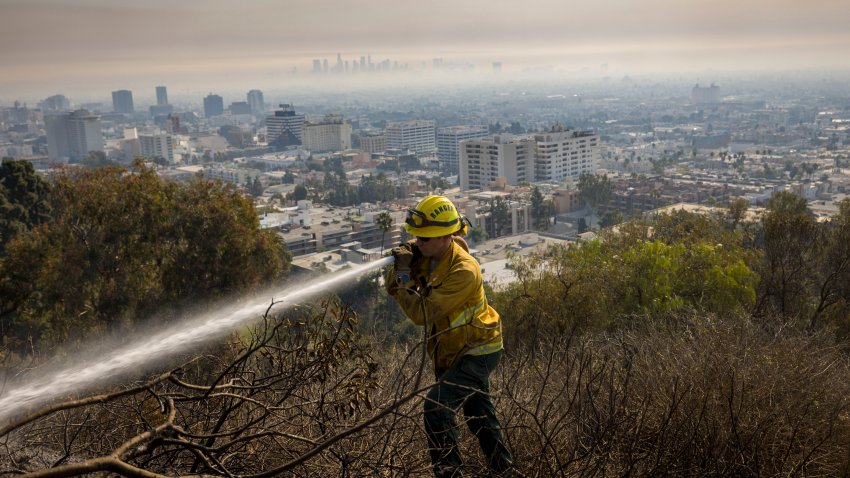 Firefighters work to extinguish spot fires on a hillside