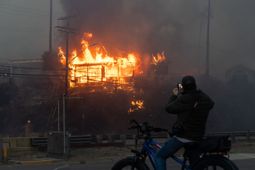 Flames from a brush fire pushed by gusting Santa Ana winds burn a home on January 7, 2025 in Pacific Palisades, Los Angeles, California.