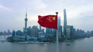 The Chinese national flag fluttering with the Lujiazui Financial District in the background.