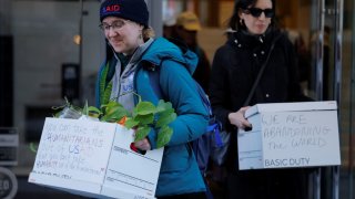 Recently fired U.S. Agency for International Development (USAID) staff carry boxes with a message as they leave work and are applauded by former USAID staffers and supporters during a sendoff outside USAID offices in Washington, D.C., U.S., February 21, 2025.