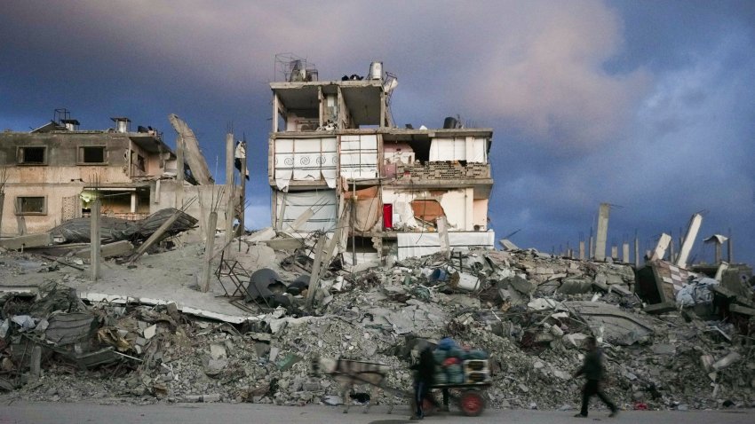 A man pushes a cart past a house that remains partly standing, but with sheets serving as makeshift walls, in an area largely destroyed by the Israeli army’s air and ground offensive in Gaza City, Gaza Strip, Wednesday, Feb. 5, 2025.