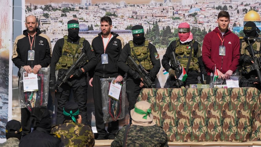 Israeli hostages Iair Horn, 46, left, Sagui Dekel Chen, 36, center left, and Alexander Troufanov, 29, right, are escorted by Hamas and islamic Jihad fighters as they are handed over to the Red Cross in Khan Younis, Gaza Strip, Saturday, Feb. 15, 2025. (AP Photo/Abdel Kareem Hana)
