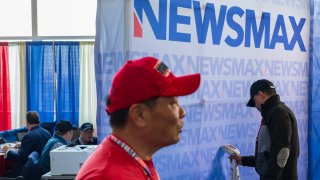 A NEWSMAX television crew member steam irons a backdrop during the Conservative Political Action Conference (CPAC) in National Harbor, Maryland, on Saturday, February 24, 2024.