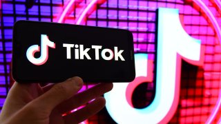 Photo illustration shows the TikTok logo displayed on a mobile phone screen.