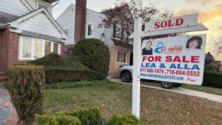 Sold realty sign in front of small older home in Queens, New York.