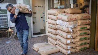 The owner of rice shop Tadao Koike carries a bag of rice at his shop in Tokyo on February 14, 2025.