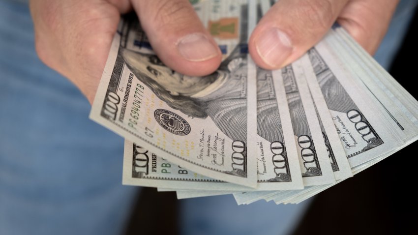 A man in a white shirt holds money, counts it and offers it to another. Close up male hand Counting and holding money us dollar. The concept of financial business and crisis.