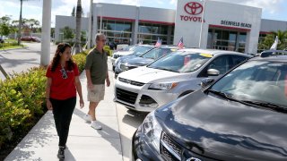 A salesperson (left) shows vehicles to a shopper at a Toyota dealership.