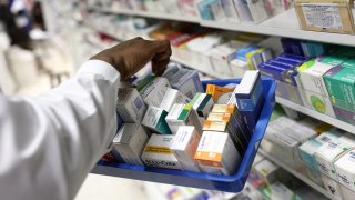 A pharmacist collects medications for prescriptions at a pharmacy.