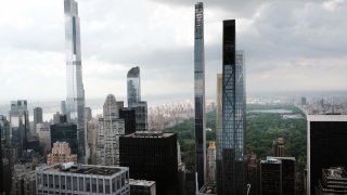 People walk by a view of residential luxury towers along nicknamed Billionaires Row, a stretch of 57th Street that holds the majority of Manhattan’s supertall luxury towers on May 16, 2022 in New York City.