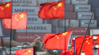 Chinese national flags flutter on boats near shipping containers at the Yangshan Port outside Shanghai, China, February 7, 2025. 