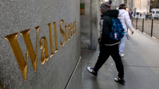 People walk along Wall Street by the New York Stock Exchange (NYSE) on March 11, 2025 in New York City.