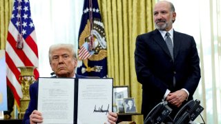 President Donald Trump holds an executive order about tariffs increase, flanked by U.S. Commerce Secretary Howard Lutnick, in the Oval Office of the White House in Washington, D.C., U.S., February 13, 2025. 