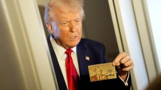 U.S. President Donald Trump holds “The Trump Card” as he speaks with journalists on board Air Force One en route to Miami, Florida, on April 3, 2025.