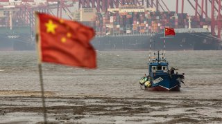Shipping containers and gantry cranes beyond a fishing boat near the Yangshan Deepwater Port in Shanghai, China, on Wednesday, Dec. 6, 2023. China’s trade figures are scheduled for release on Dec 7.