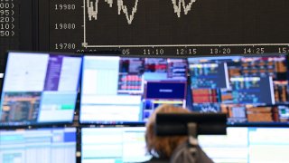 A trader watches her monitors on the trading floor of the Frankfurt Stock Exchange in front of the display board showing the Dax curve.