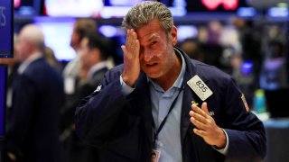 A trader puts on sunscreen, during the closing bell, on the floor at the New York Stock Exchange on April 10, 2025.