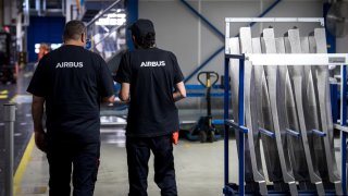 Workers walk at the Airbus’ engine pylons assembly line in Toulouse, southwestern France, on 18 November 2024.