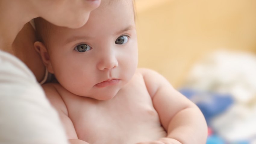 Close-up of mother holding baby in hands.