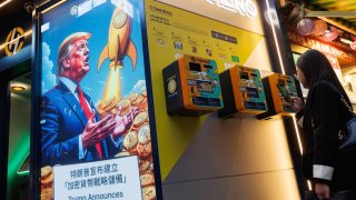 People walk past an advertisement feature Donald Trump with Bitcoin in Hong Kong.