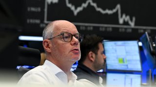 On the trading floor of the Frankfurt Stock Exchange, traders watch their monitors in front of the display board showing the Dax curve on April 9, 2025.