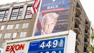 An image of President Donald Trump, marking his first 100 days in office, is seen on the Heritage Foundation, next to an Exxon station on Capitol Hill on Monday, May 5, 2025.