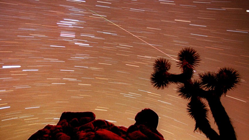 FILE – A meteor streaks through the sky over Joshua trees and rocks at Joshua Tree National Park in Southern California’s Mojave Desert in this 30-minute time exposure ending at 1:15 a.m. PST, Nov. 17, 1998. Stars moving through the sky as the Earth rotates are seen as a series of short lines across the frame.