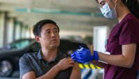 Pasadena, CA – October 12: Justine Castillo Martinez, LVN, right, takes a moment to show her patient Phillip Soon, 38, the syringe during a flu and COVID-19 vaccination clinic at Kaiser Permanente Pasadena on Thursday, Oct. 12, 2023, in Pasadena, CA. Soon was getting both the flu and COVID-19 vaccination.