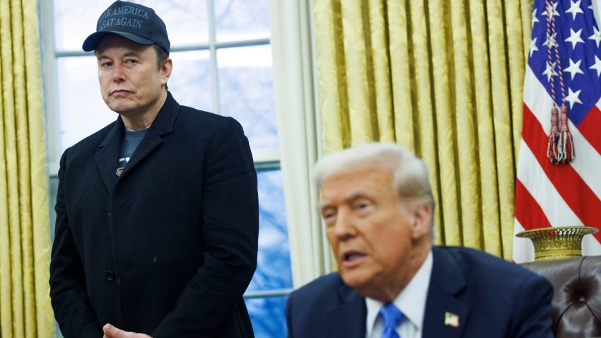 Elon Musk stands behind Donald Trump in the Oval Office