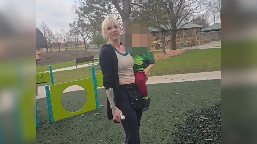Woman stands in playground with child