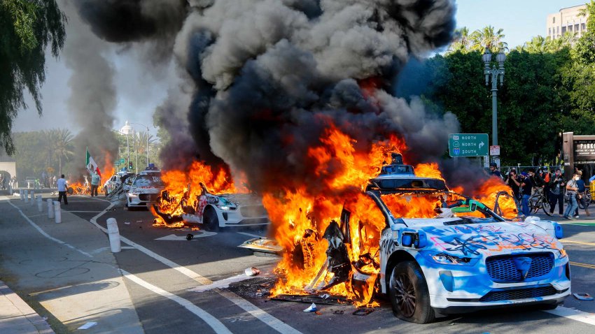 A row of Waymo vehicles burn on a street during an anti-ICE protest in downtown Los Angeles, California, on June 8, 2025.