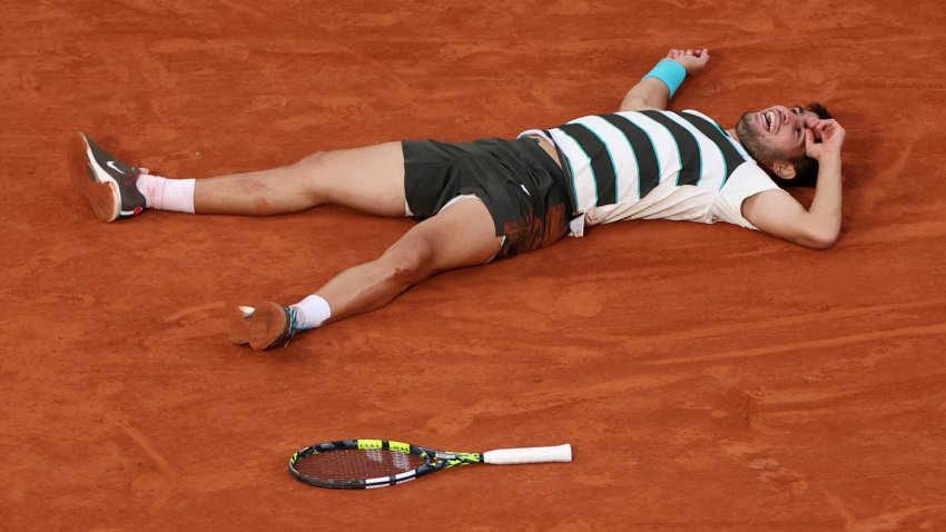Carlos Alcaraz lies on the ground as he celebrates his victory