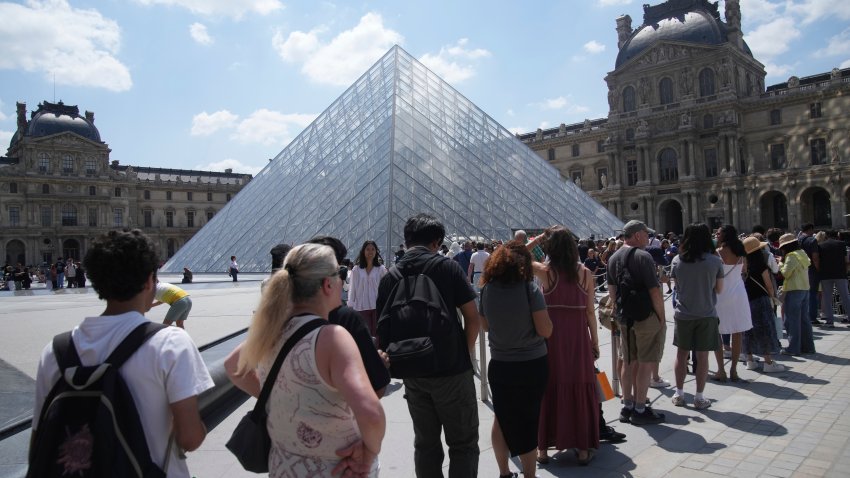 Tourists wait in line outside the Louvre museum which failed to open on time Monday, June 16, 2025 in Paris.
