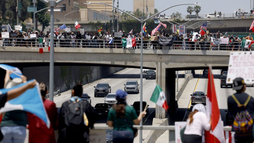 Protesters wave flags on the overpass of highway 101 during the "No Kings" demonstration in downtown Los Angeles .