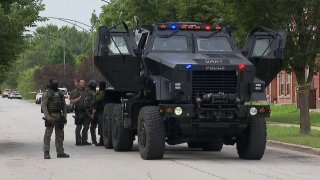 A large black SWAT vehicle is seen in Gary, Indiana, with multiple officers in body armor standing outside of the 10-foot-tall vehicle.