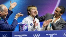 MILAN, ITALY - February 17: Alysa Liu of the United States with coaches Phillip DiGuglielmo and Massimo Scali awaiting her score after performing her routine during the Figure Skating, Women's Singles Skating, Short Program at the Milano Ice Skating Arena at the Milano Cortina Winter Olympic Games 2026 on February 17th, 2026 in Milan, Italy. (Photo by Tim Clayton/Getty Images)